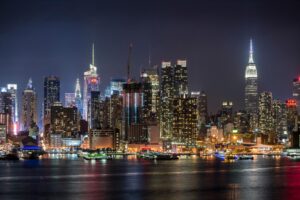 Stunning view of the illuminated New York City skyline reflecting on the Hudson River at night.